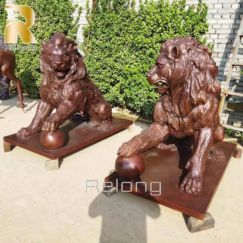 bronze lion statue with paw on ball