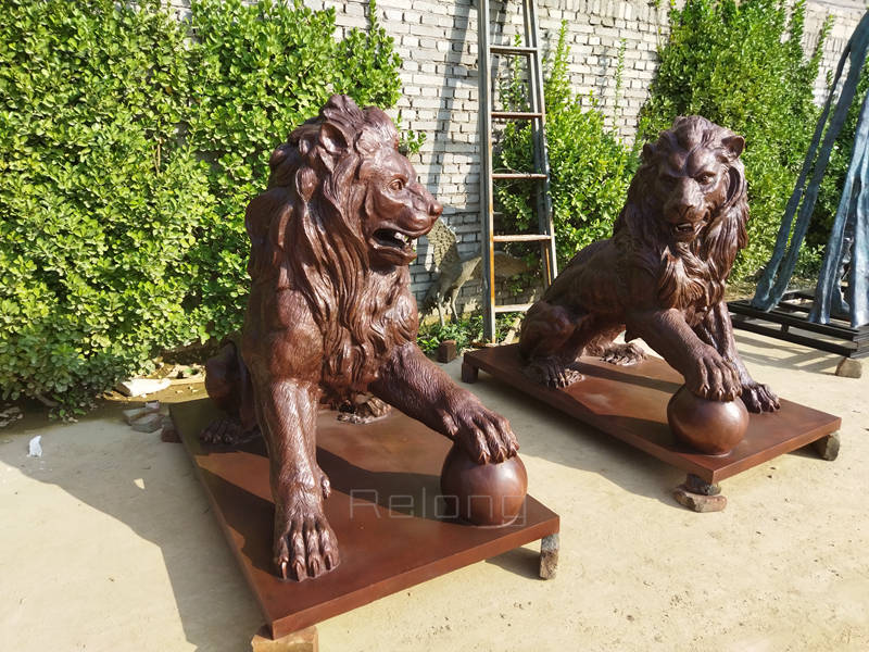 outdoor bronze lion statue with paw on ball (1)