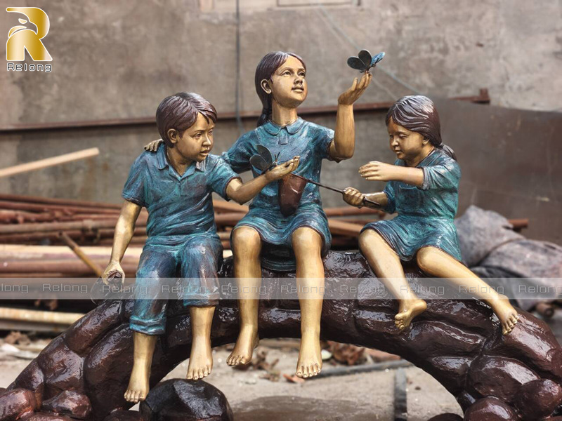 bronze children sculpture on log